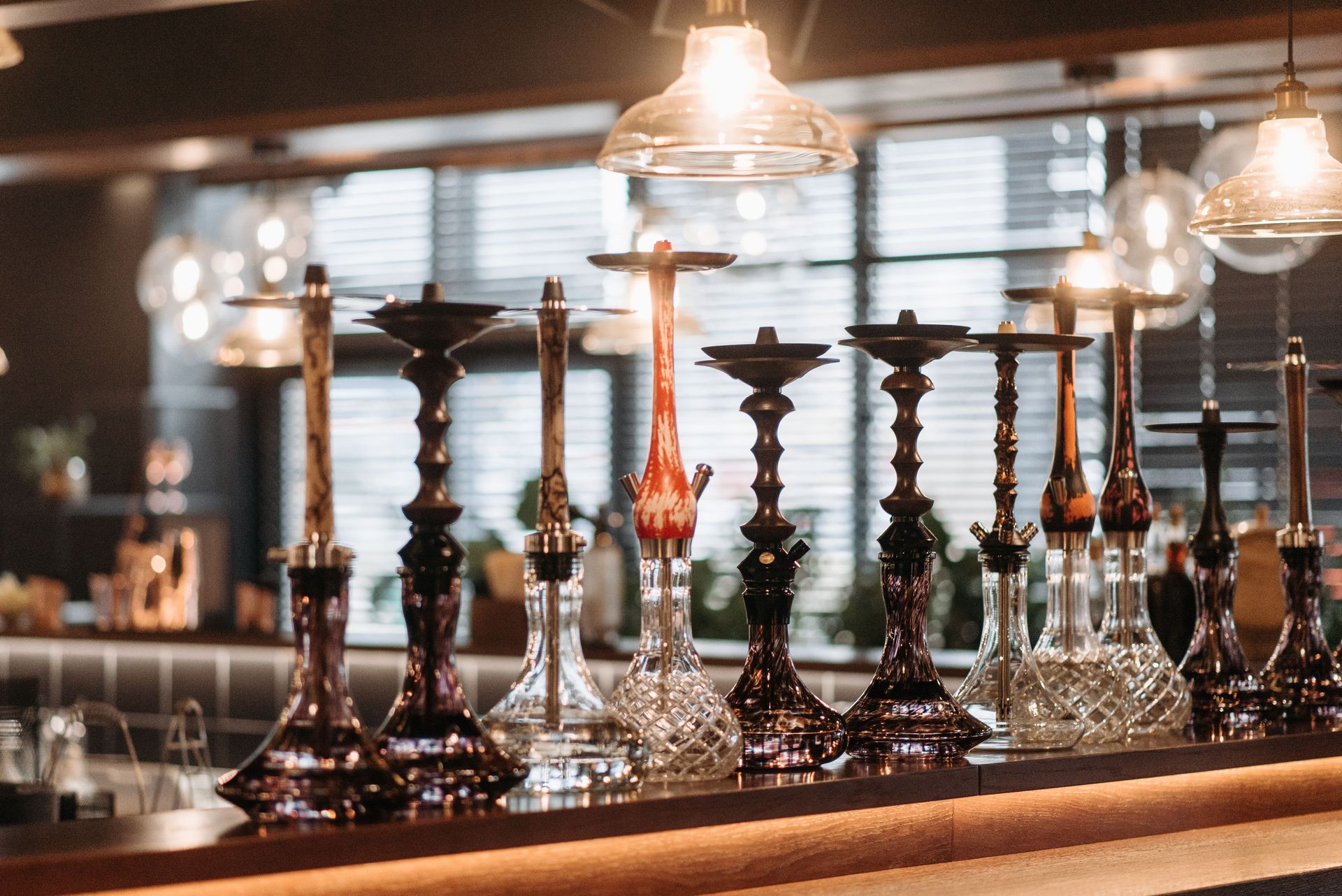 A stylish array of hookahs displayed on a bar counter with ambient lighting.