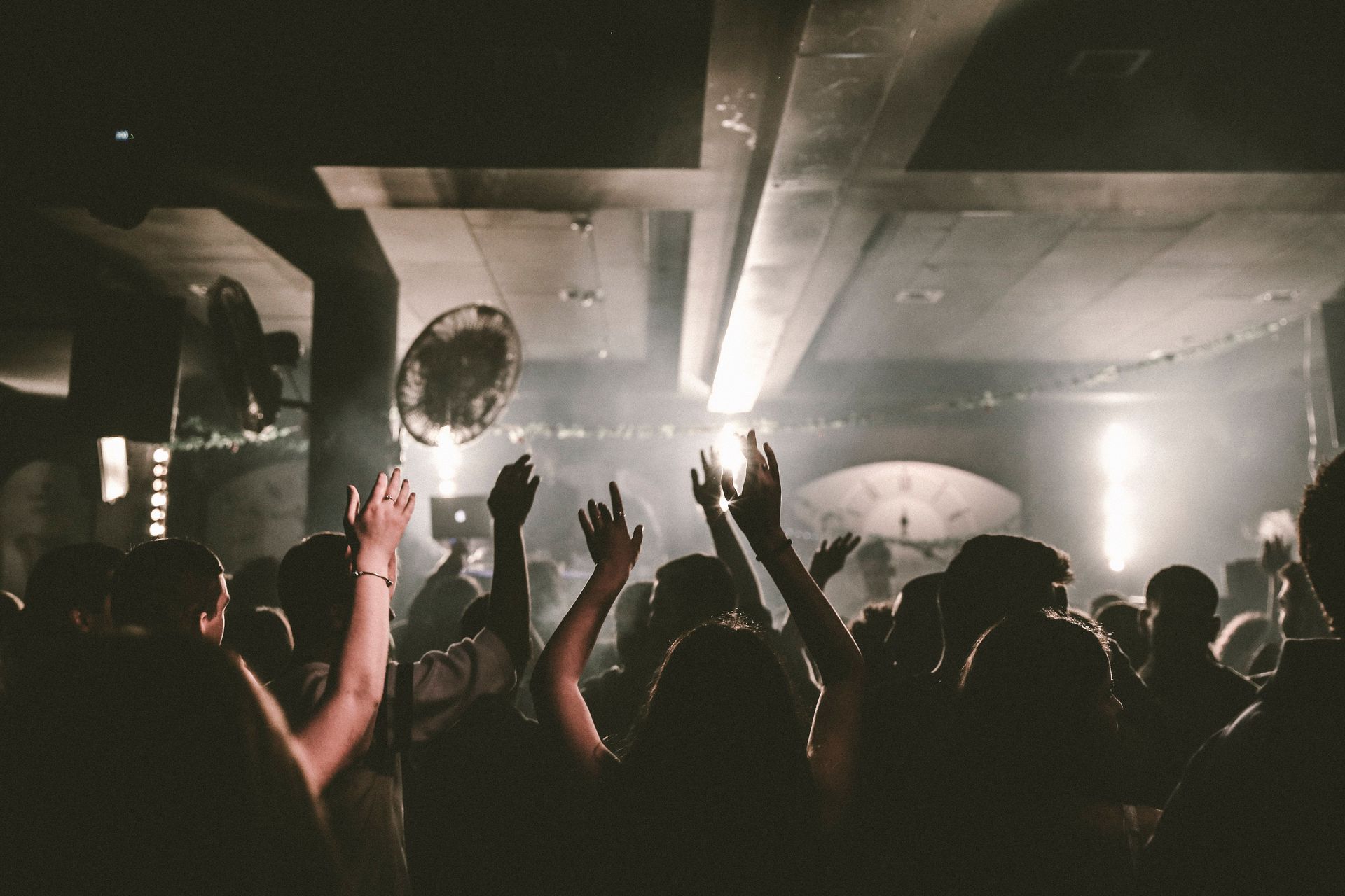 A lively scene of people dancing with raised arms at a vibrant nightclub event.